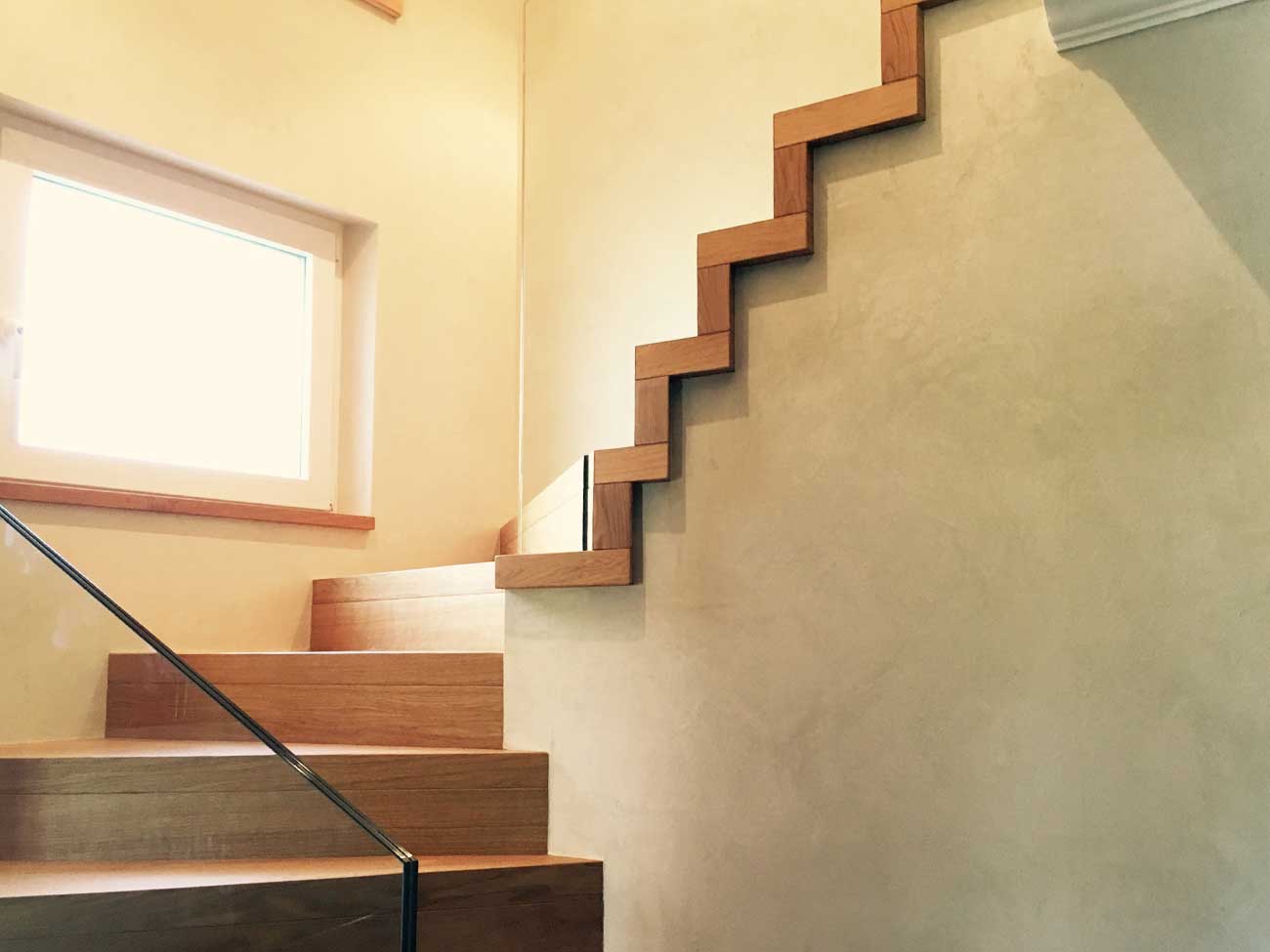 Betontreppe mit Holzstufen, perfekt in die Fassadengestaltung des Sockels integriert